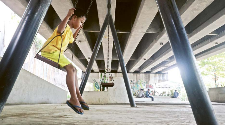 FASILITAS PUBLIK: Seorang anak bermain ayunan di taman kolong flyover Kedungkandang kemarin siang.
