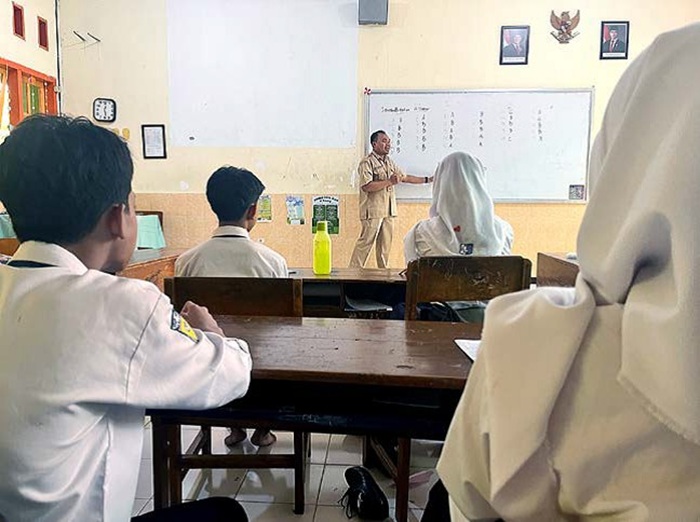 SUDAH PENGAJUAN: Salah satu guru di SMPN 8 Malang mengoreksi jawaban tugas untuk murid-muridnya, kemarin (27/8).