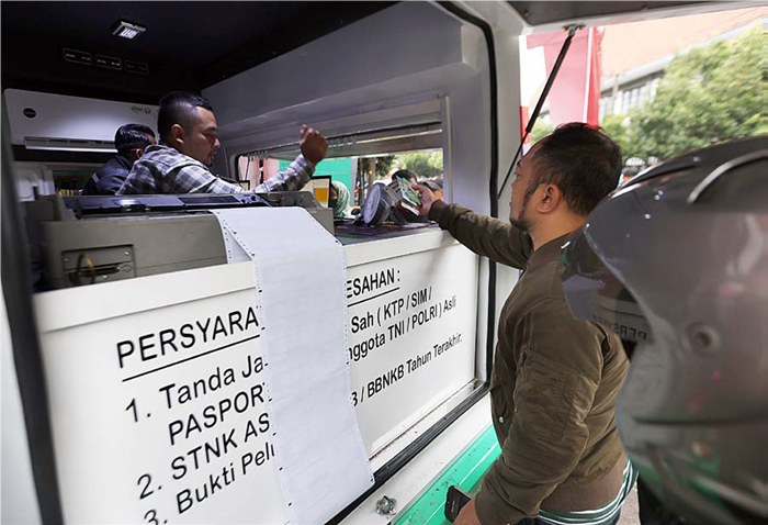 KESADARAN MENINGKAT: Salah satu warga memenuhi kewajiban membayar pajak kendaraan di Samsat Keliling di Alun-Alun Merdeka, kemarin sore. Hingga bulan Agustus realisasi pajak mencapai 67 persen.