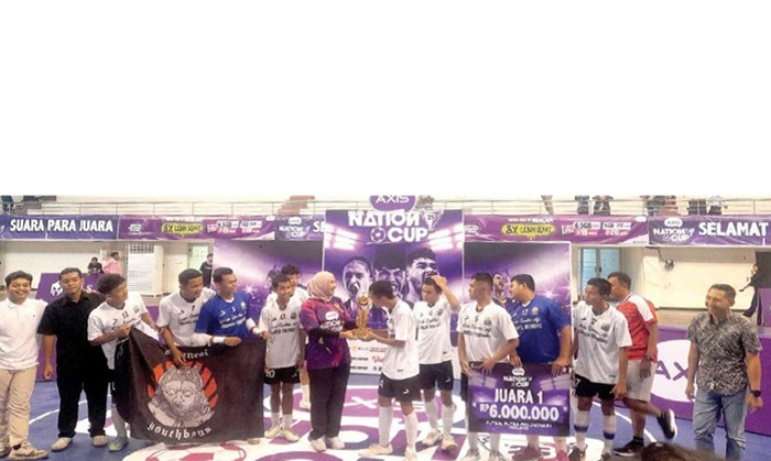 MELAJU KE JENJANG PROVINSI: Head of Sales XLSMART Greater Malang Deri Puspitayani menyerahkan trofi juara AXIS Nation Cup 2025 kepada kapten tim futsal SMAN 1 Singosari di GOR Ken Arok, Minggu (31/8).