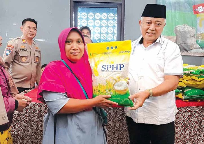 DEMI MASYARAKAT: Bupati Malang H M. Sanusi menyerahkan beras murah ke salah satu warga di Gedung Cindewilis, Pakisaji kemarin (1/9).