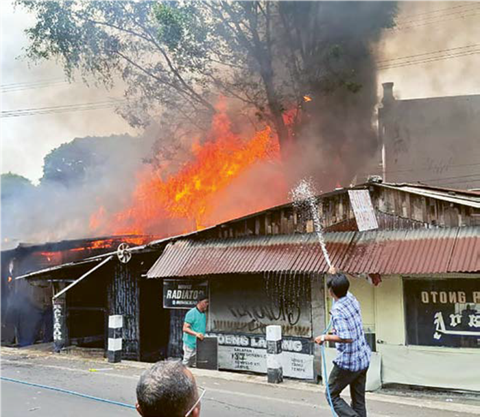 GUDANG PENYIMPANAN KAYU: Warga berusaha membantu memadamkan api yang melalap bangunan semi permanen di Jalan Ikan Tombro, Kelurahan Lowokwaru dengan alat seadanya, kemarin siang.
