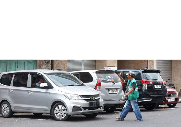 SUMBER PENDAPATAN: Seorang juru parkir menata kendaraan di Jalan Pasar Besar kemarin (7/9).