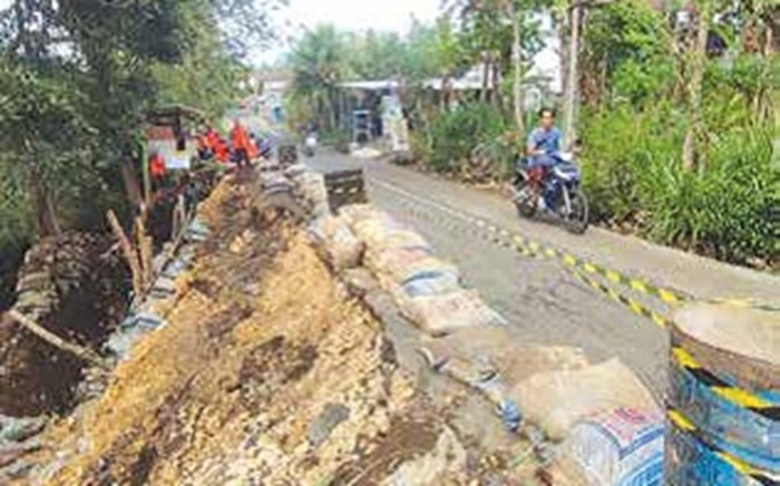 CEGAH LONGSOR: Beberapa pekerja memasang Tembok Penahan Tanah (TPT) dari karung berisi pasir di Jalan Desa Bantur, Kecamatan Bantur kemarin (17/9).