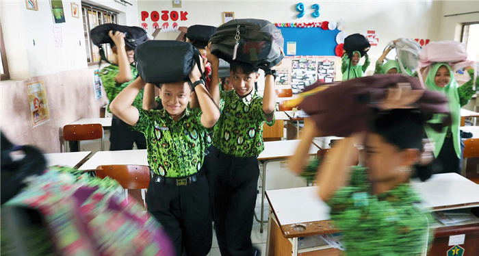 BEKAL SURVIVAL: Pelajar SMP Negeri 3 Malang melakukan simulasi jika terjadi gempa bumi, kemarin. Mereka diharuskan berkumpul di titik kumpul evakuasi di lapangan sekolah.