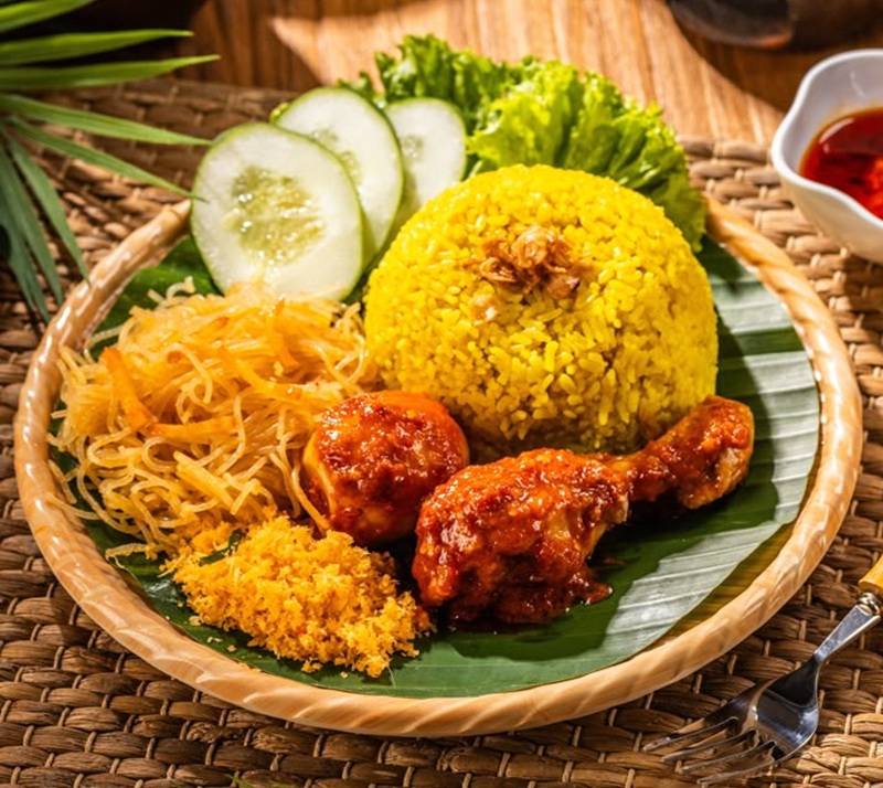 TRADISIONAL: Nasi kuning lauk ayam balado, mi, dan sayuran dengan alas daun pisang