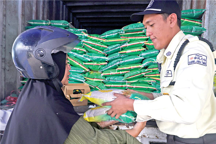LEBIH MURAH: Petugas Bulog Cabang Malang membantu penyaluran beras SPHP kepada warga kemarin.