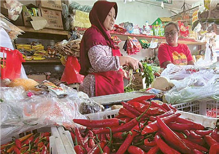 MAKIN PEDAS: Seorang pedagang cabai di Pasar Pakisaji melayani pelanggannya kemarin (24/9)