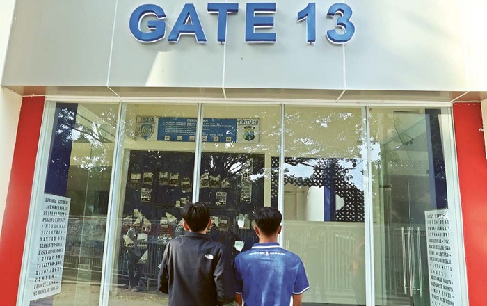 MENOLAK LUPA: Dua Aremania berdoa di depan Gate 13 Stadion Kanjuruhan. Tiga tahun tragedi Kanjuruhan diperingati dengan berbagai cara.