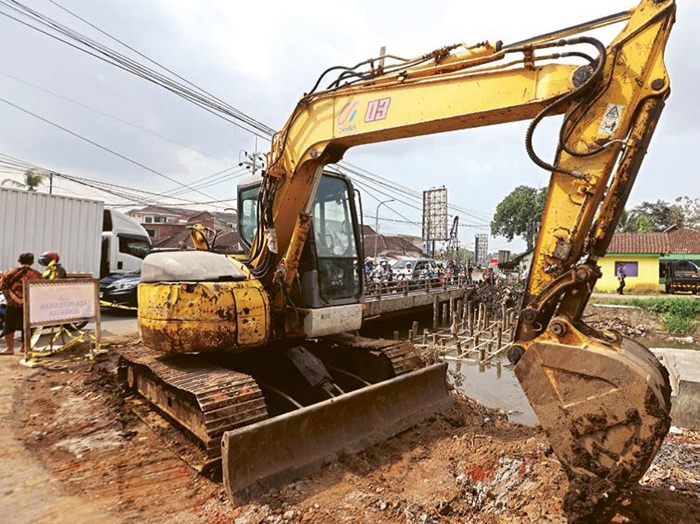DIKEBUT: Alat berat diterjunkan untuk pelebaran jembatan di Jalan KH Malik, Kedungkandang, Kota Malang kemarin (2/10).