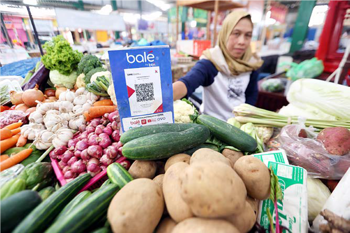 SIAP E-RETRIBUSI: Seorang pedagang sayur di Pasar Klojen menunjukkan QR Code untuk melayani pembayaran dari konsumen kemarin (7/10).