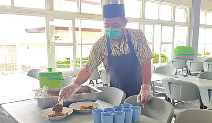 PASTIKAN AMAN: Seorang pramusaji menyiapkan makanan di Al Hikmah International Islamic Boarding School (IIBS) Kota Batu kemarin (16/10).