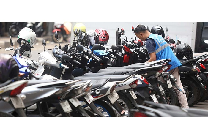 TUNGGU ATURAN BARU: Seorang juru parkir menata sepeda motor di ruas Jalan Yulius Usman, Kecamatan Klojen kemarin.