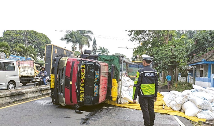 PENGEMUDI KURANG KONSENTRASI: Truk bernopol W 8731 UV terguling di Jalan Raya Losari, Singosari, kemarin pagi. Rekayasa lalu lintas harus dilakukan petugas untuk mengurai kemacetan.