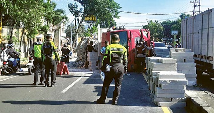 KURANG KONSENTRASI: Petugas butuh waktu sekitar dua jam untuk melakukan evakuasi terhadap truk bermuatan bata ringan yang terguling di Jalan Raya Wahidin, Lawang, kemarin pagi.