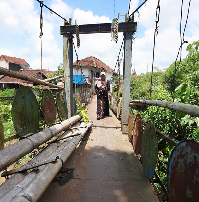 BUTUH PERBAIKAN: Warga melintasi jembatan Kampung Baru Kepuh di Kelurahan Bakalankrajan, Kecamatan Sukun yang rusak sejak lima tahun lalu.