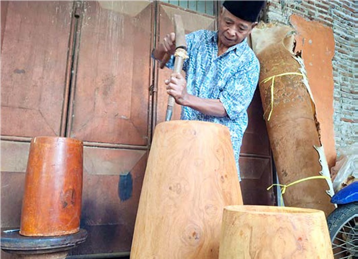 JAGA WARISAN: Diono memahat kayu nangka untuk dijadikan gendang di halaman rumahnya kemarin siang.