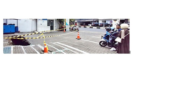 BEKAS IRIGASI: Halaman kantor BSI Malang di Jalan Letjen Sutoyo yang ambles masih dipasangi garis pembatas berwarna kuning kemarin (27/10).