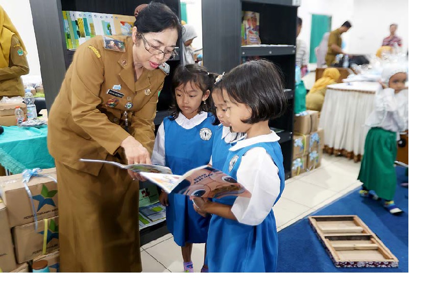 TINGKATKAN LITERASI: Kepala Dispussipda Kota Malang Yayuk Hermiati mendampingi pelajar yang membaca buku di sela penyaluran bantuan dari Perpusnas di Gedung Kartini kemarin (27/10).