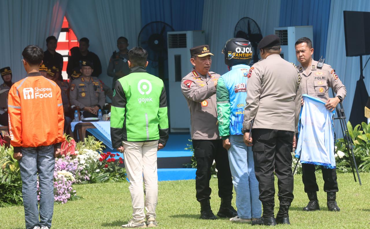 Kapolri Jenderal Pol Listyo Sigit Prabowo memasangkan rompi kepada pengemudi ojek online saat Apel Ojol Kamtibmas di Stadion Gajayana, Jumat (31/10).  (Darmono/Radar Malang)