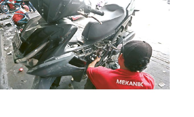 SETELAH ISI BBM: Seorang mekanik bengkel di kawasan Klojen memperbaiki sepeda motor yang mengalami masalah setelah mengisi bensin di SPBU kemarin.