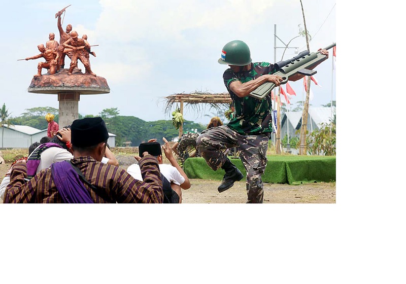 RANGKUL ANAK-ANAK MUDA: Warga Kelurahan Wonokoyo, Kecamatan Kedungkandang melakukan aksi teatrikal pertempuran antara warga pribumi dengan pasukan Belanda di depan monumen Hamid Rusdi, kemarin (10/11)