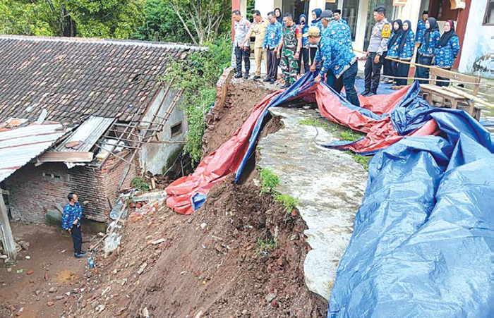 BENCANA: Personel BPBD Kabupaten Malang, aparat kepolisian dan TNI meninjau lokasi longsor yang menimpa gedung SDN 1 Bedalisodo, Wagir kemarin.