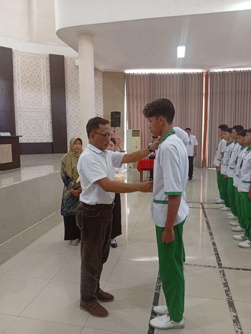 BERI SEMANGAT : Kepala SMKN 2 Malang Dr Drs Hari Mulyono MT (kiri) menyematkan atribut PKL kepada Shendi Fadhila dari XII LPKC 4.