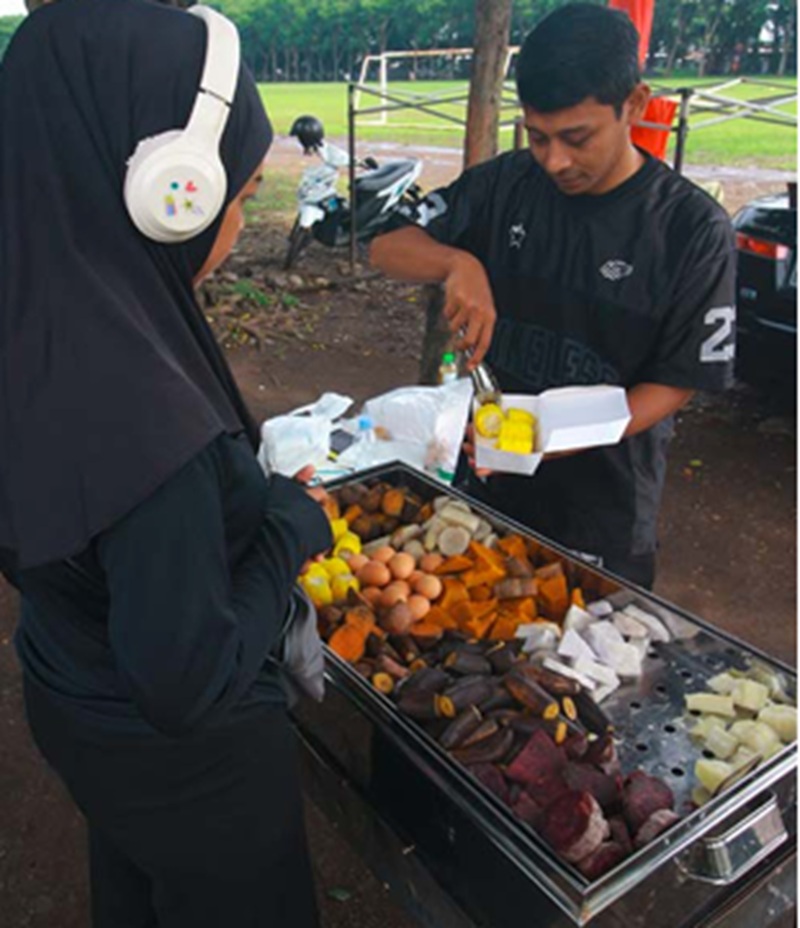 MENYEHATKAN: Seorang mahasiswa membeli aneka polo pendem di Lapangan Rampal kemarin pagi. Jajanan kukusan tersebut ramai diburu oleh warga yang selesai berolahraga.