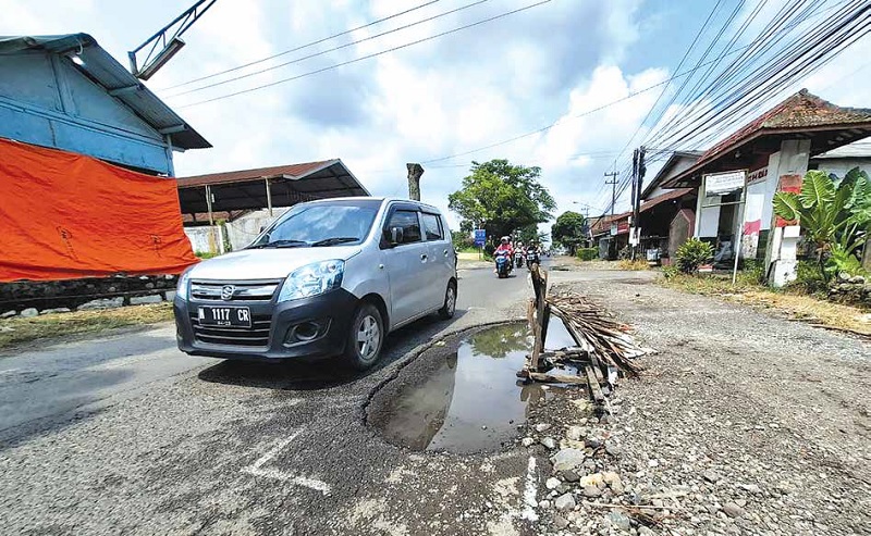 HARUS BERHATI -HATI : Salah satu pengendara melintasi jalan berlubang yang ada di Dusun Sanggrahan, Desa Mangunrejo, Kecamatan Kepanjen, kemarin.