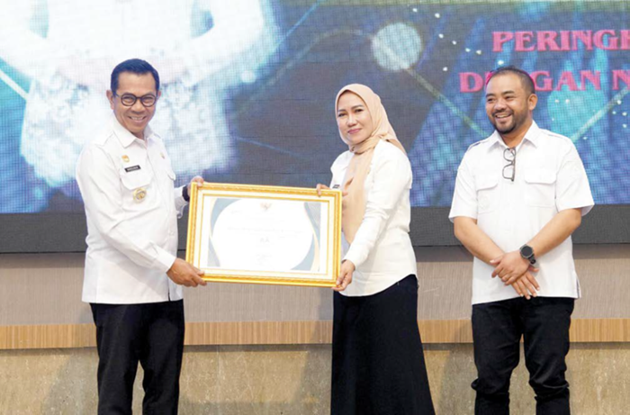 BERI PENGHARGAAN: Wali Kota Batu Nurochman menyerahkan penghargaan kepada Kepala Disperpusip Kota Batu Esty Dwiastuti di Hotel Aston Inn kemarin (26/11).