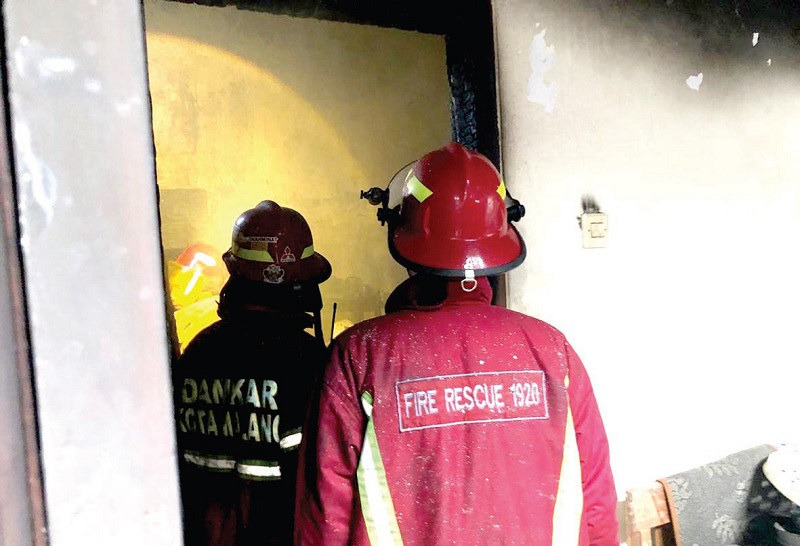 AKIBAT KORSLETING: Petugas Pemadam Kebakaran Kota Malang memadamkan api yang membakar gudang rumah di Sumbersari kemarin.