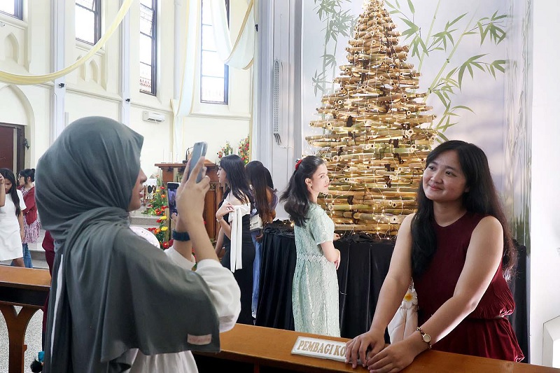 TOLERANSI: Salah satu umat Kristiani, Clara Sinartya ditemani rekannya yang beragama Islam di Gereja Katolik Hati Kudus Yesus Kayutangan kemarin (25/12).