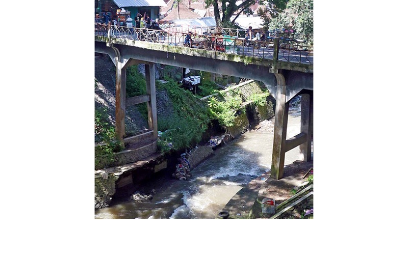 INFRASTRUKTUR: Pengunjung Pasar Splendid melintasi Jembatan Brawijaya yang mengalami kerusakan bagian plengsengan dan fondasi.