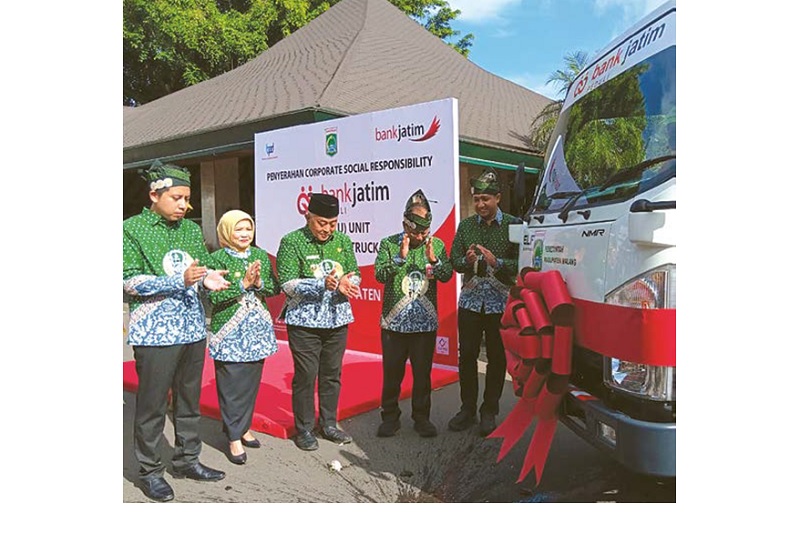 SIMBOLIS: Pemecahan kendi dilakukan di depan arm roll truck bantuan dari Bank Jatim Cabang Kepanjen, kemarin.