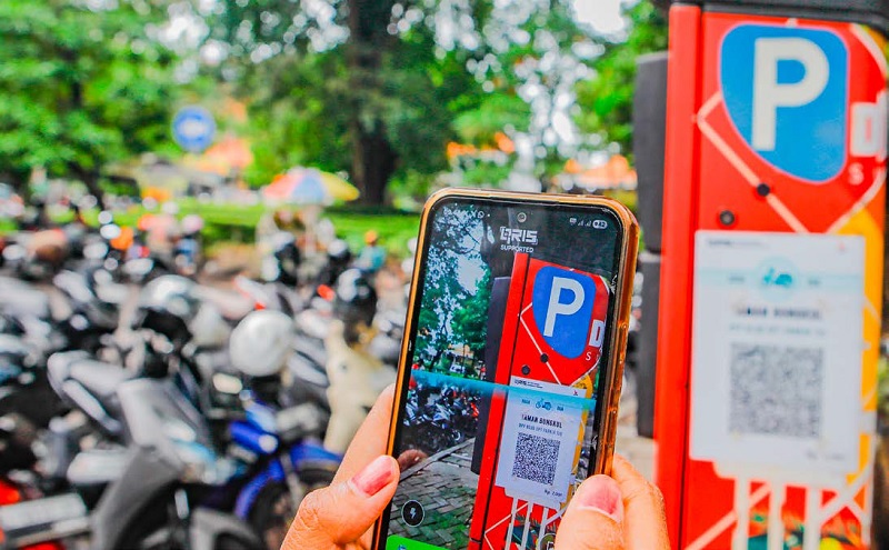 BUTUH PENYEMPURNAAN: Pengendara memindai kode QRIS pada rambu parkir digital di kawasan Taman Bungkul, Surabaya, kemarin siang.