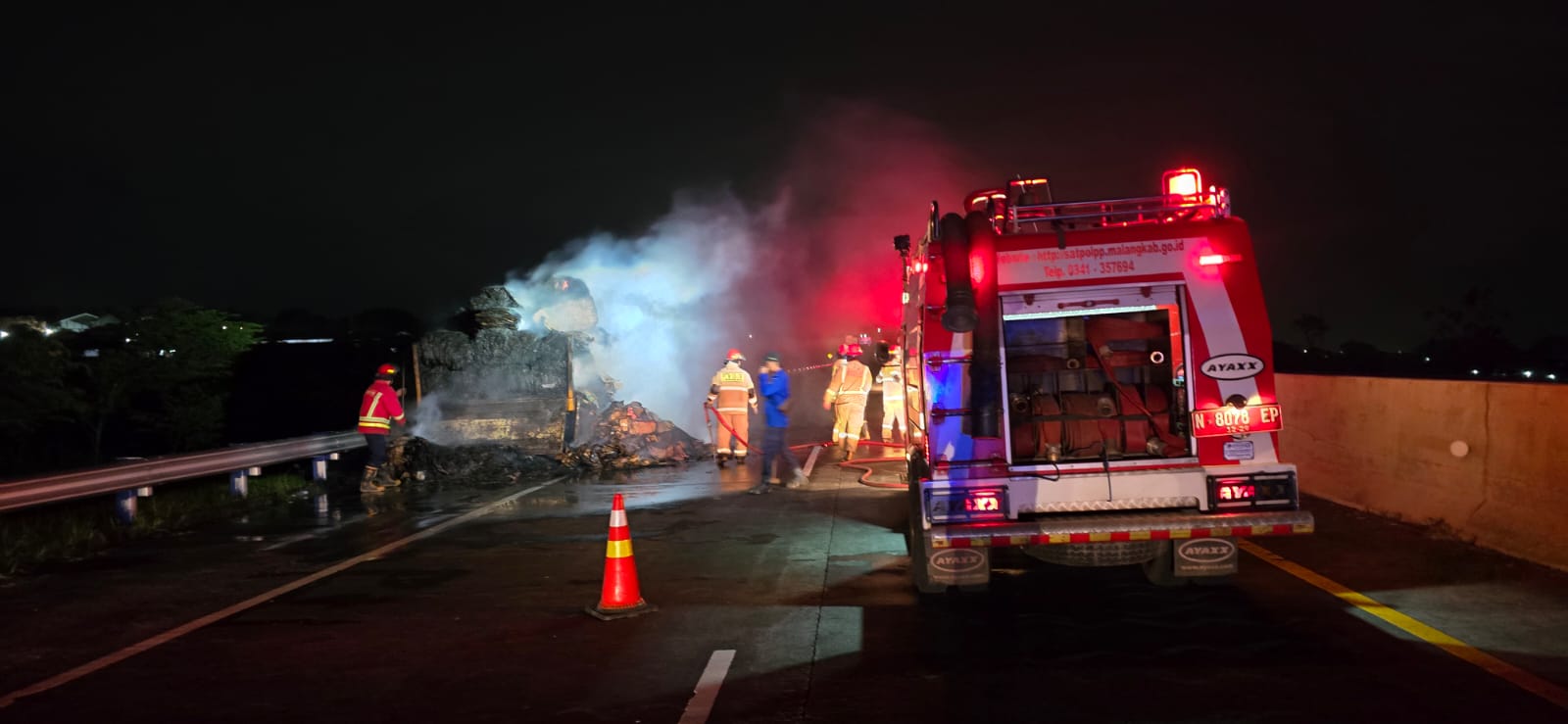 Petugas damkar memadamkan truk yang terbakar di tol Malang-Pandaan pada Senin (5/1) malam. (Unit Gakkum Satlantas Polres Malang)
