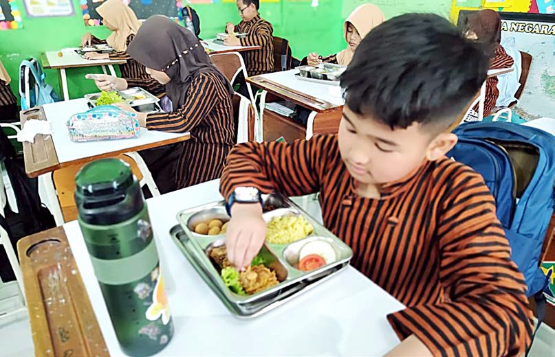 BEROPERASI LAGI: Pelajar SDN 1 Dinoyo mendapatkan paket MBG lagi setelah sebelumnya libur lima hari.