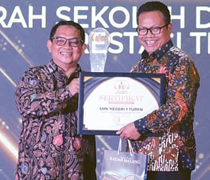 MENDAPAT APRESIASI: Direktur Jawa Pos Radar Malang Tauhid Wijaya menyerahkan trofi dan piagam penghargaan kategori Anugerah Sekolah dengan Capaian Prestasi Tinggi kepada Kepala Kepala SMKN 1 Turen