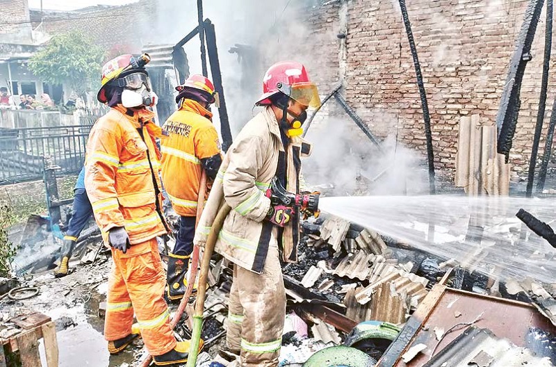 KARENA LPG BOCOR: Petugas Damkar Kota Malang memadamkan api yang melalap rumah Erwan Susanto, kemarin.