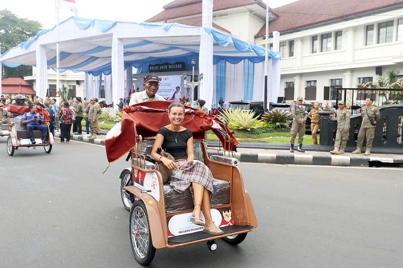 VERIFIKASI PENERIMA: Wisatawan asing ikut menjajal becak listrik yang dibagikan di Balai Kota Malang, kemarin.