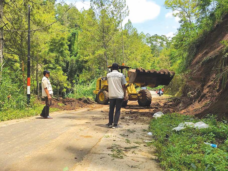 BENCANA: Satu unit alat berat diterjunkan untuk membersihkan material longsor yang menutupi ruas jalan kemarin (20/1).