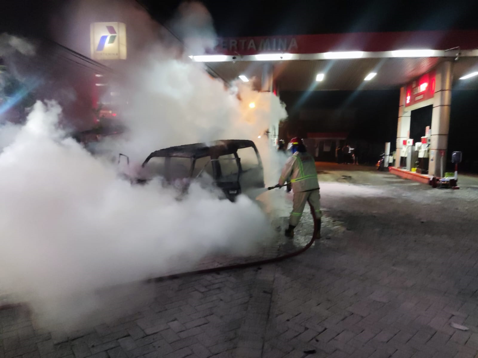 HANGUS: Petugas Damkar Kabupaten Malang memadamkan kobaran api yang menghanguskan mobil Suzuki Carry di area SPBU Dilem, Kecamatan Kepanjen.