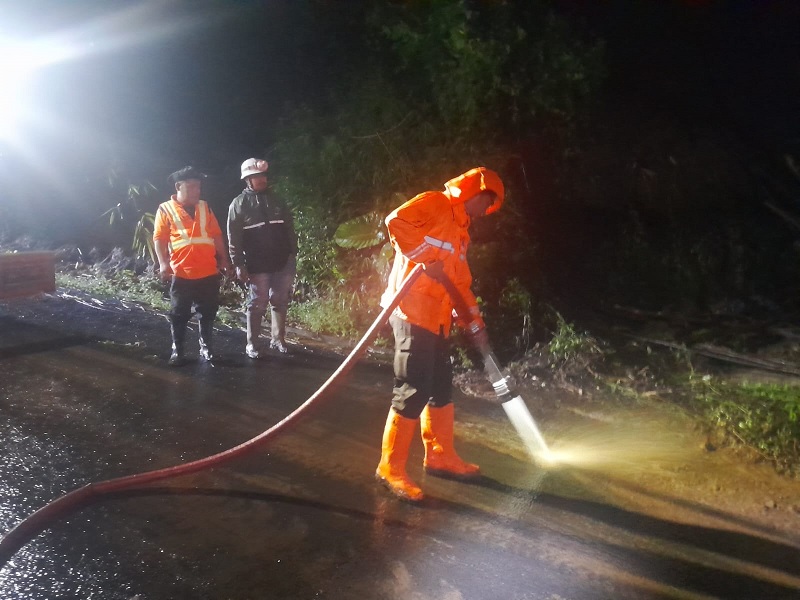 MULAI NORMAL: Personel BPBD Kabupaten Malang membersihkan material longsor yang menutupi ruas jalan Desa Sukomulyo, Pujon menggunakan air kemarin.