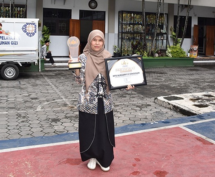 BERPRESTASI: Kepala MTs Almaarif 01 Singosari Dwi Retno Palupi menunjukkan piagam penghargaan di halaman sekolah kemarin.
