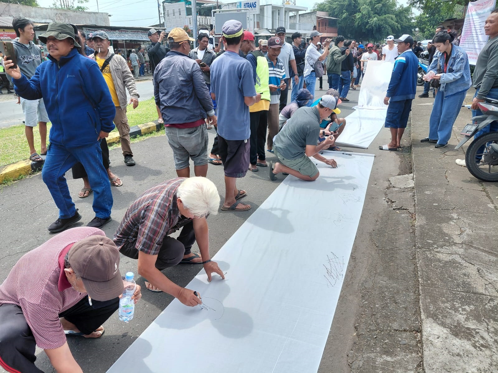 SAMPAIKAN ASPIRASI: Peserta aksi membubuhkan tanda tangan di sela-sela menyampaikan aspirasi kemarin (26/1).