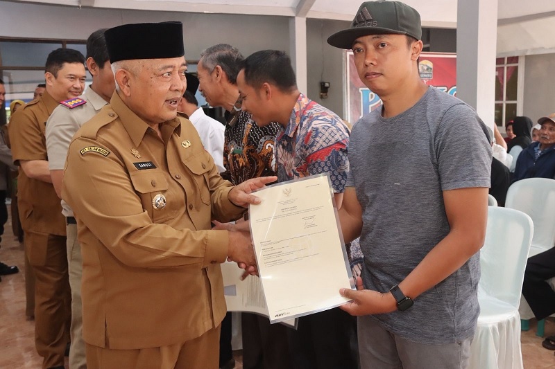 REDISTRIBUSI: Bupati Malang H M. Sanusi (kiri) menyerahkan sertifikat kepada warga di Kecamatan Tirtoyudo, Selasa (27/1).