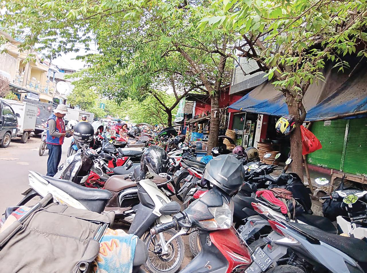 SUMBER PENDAPATAN: Jukir menjaga deretan motor yang parkir di depan Pasar Kepanjen. (INDAH MEI YUNITA/RADAR MALANG)
