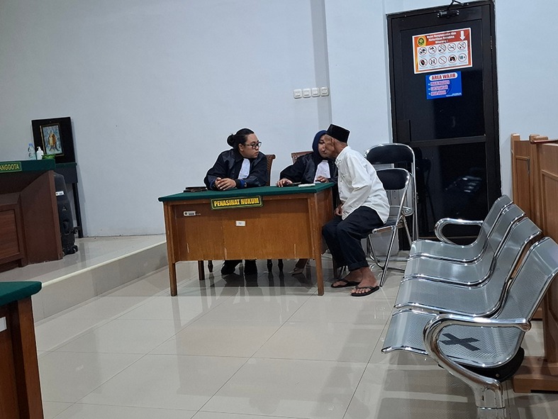 DIVONIS 12 TAHUN: Aripin, 66, warga Kecamatan Poncokusumo berdiskusi dengan penasihat hukumnya di PN Kepanjen, Senin sore (2/2).
