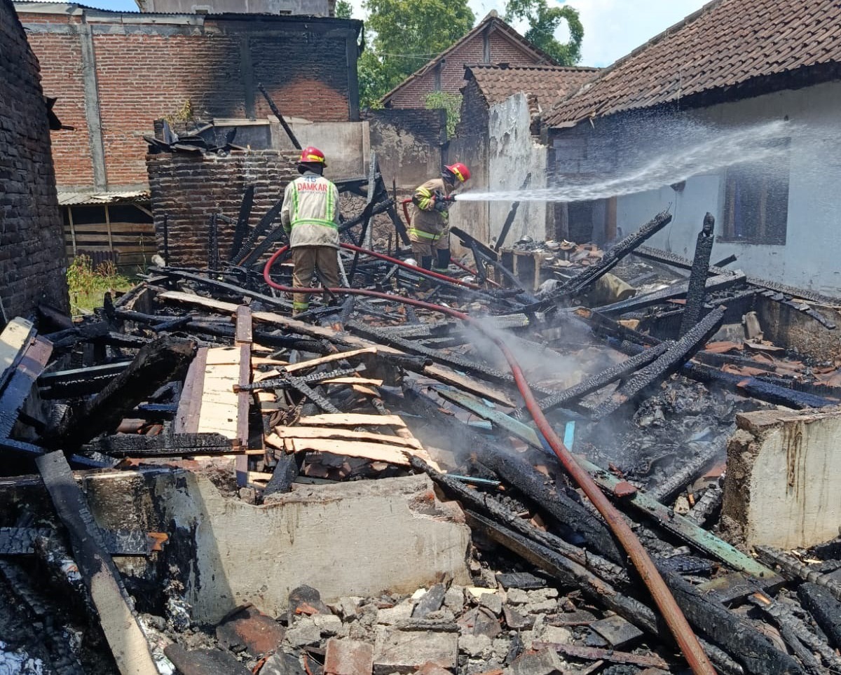DIDUGA KORSLETING: Dua petugas Damkar Kabupaten Malang berupaya memadamkan sisa-sisa api yang melalap sebuah rumah di RT 5/RW 9 Dusun Tumpangrejo, Desa Kebobang, Kecamatan Wonosari, kemarin siang.